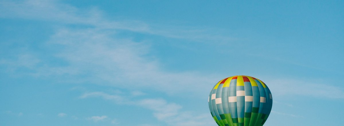 Decorative element: Multi-coloured hot air balloon in the blue sky on a sunny day